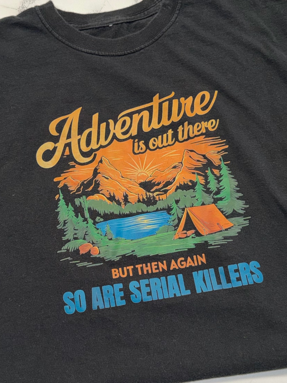 “Adventure is out there but then again so are serial killers” T-shirt in Black